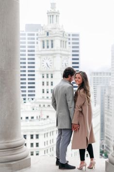 a man and woman standing next to each other in front of tall buildings