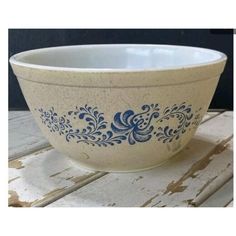 a blue and white bowl sitting on top of a wooden box next to a flower