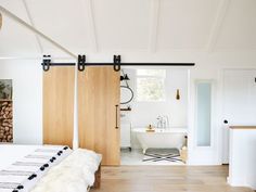 an open door leading to a bathroom with white walls and wood flooring, along with a bathtub in the background