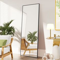 a mirror sitting on top of a wooden floor next to a chair and potted plant