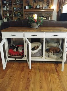 two dogs are sleeping in their beds under the console table that is built into the wall