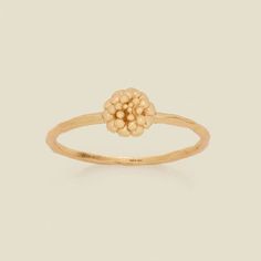 a yellow gold ring with flowers on it's center and two small beads in the middle