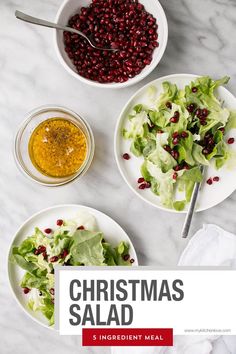 christmas salad with dressing in bowls on a marble countertop next to a bowl of lettuce and pomegranate