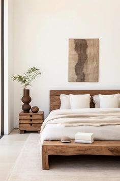 a bed with white linens and pillows in a bedroom next to a painting on the wall