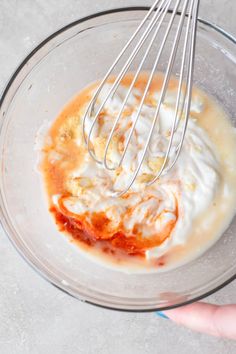 someone is mixing ingredients in a bowl with a whisk