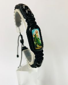 "Pulsera de San Judas Tadeo hecha a mano de doble tejido estilo Macrame con hilo reforzado en color negro. San Judas Tadeo el patrono de caso imposible. Pulsera ajustable y expandible para hombre o mujer con minimo cierre de 7\" pulgadas hasta maximo de 9\" pulgadas. Tableta de madera (1\"x 1/2\" x 1/4\" ) color verde obscuro con imagen de alta definicion San Judas en ambos lados y cubierta con resina Hilo reforzado #18 color Negro Bolas gemstone Onyx negro 8mm Nudo: 12" Black Woven Braided Bracelets For Gift, Black Woven Braided Bracelets As Gift, Black Woven Braided Bracelet For Gifts, Black Braided Bracelets As Gift, Adjustable Black Woven Friendship Bracelets, Black Woven Bracelet Gift, Artisan Hand Wrapped Black Bracelets, Artisan Hand Wrapped Black Bracelet, Artisan Hand-wrapped Black Bracelet