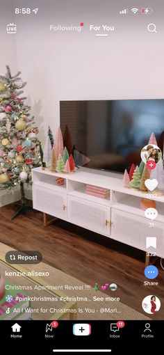 a flat screen tv sitting on top of a white entertainment center next to a christmas tree