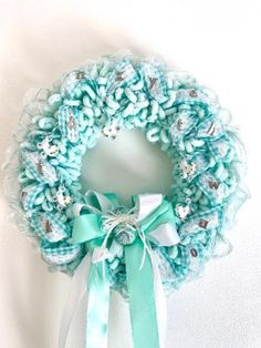 a blue and white wreath hanging on the wall next to a light green ribbon tied around it