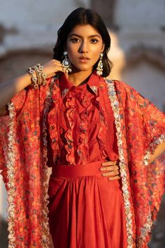 Ruby red cape with feather print and pearl, dori embroidered cutwork border. Paired with ruffle shirt and draped skirt.
Components: 3
Pattern: Printed, Embroidery
Type Of Work: Feather, pearl, dori
Neckline: Cape: Open, Shirt: Spread collar
Sleeve Type: Flared sleeves
Fabric: Flat Chiffon, Dola Silk, Organza
Color: Red
Other Details: 
Cutwork border
Lace embroidered panel
Occasion: Sangeet - Aza Fashions Feather Cape, Printed Embroidery, Border Lace, Open Shirt, Red Cape, Red Flats, Draped Skirt, Ruffle Shirt, Feather Print