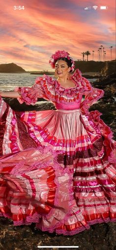 a woman in a pink dress standing on the beach