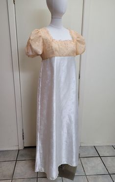 This dress has tracked shipping included within the US and Canada!    We offer a basic Regency styled gown, with the empire waist and short puffed sleeves.  The top of this dress has an apricot pink sheer overlay that has been embroidered with a scrolling design and tiny sequins.  The neckline has been trimmed with lace.  The skirt of the dress is a white satin jacquard with a dainty floral design.  Please check teh waist to hem measurement, as this is hemmed to a petite length.    *This gown ti White Regency Dress, Bridgerton Daphne, Jane Austen Emma, Historic Dresses, Bridge Dress, Jonathan Bailey, Regency Dress, 40 Dress, Historical Dresses