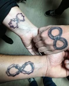 two people are holding hands with tattoos on their arms and wristbands that have the number 8 in them