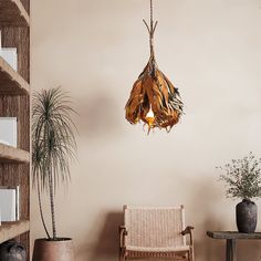 a living room with a chair, potted plants and a light fixture hanging from the ceiling