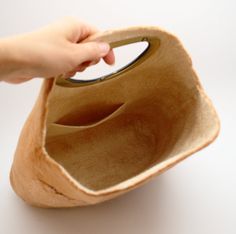 a hand holding a wooden purse on top of a white table