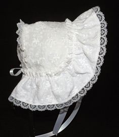 A beautiful Victorian style baby or doll bonnet. Fabric is white cotton raised embroidery. Lining is white . Bonnet has an extended back and is trimmed with white lace. Bows and extra long ties are made of white double sided satin ribbon. Size/ Measurement from under ear lobe around top of head to under other ear lobe 0-3 months / 11 inches 3-6 months / 12 inches 6-9 months / 13 inches 9-12 months / 14 inches 12-18 months / 15 inches 18-24 months / 16 inches Fitted White Bonnet With Lace Trim, White Fitted Vintage Bonnet, Fitted Cotton Bonnet With Lace Trim, Fitted White Bonnet For Baptism, White Fitted Bonnet For Baptism, White Adjustable Lace Bonnet, White Lace Adjustable Bonnet, White Cotton Bonnet For Baptism, White Bonnet