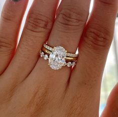 a woman's hand with two wedding rings on it and an engagement ring in the middle