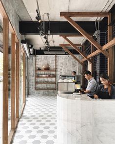 two people sitting at a counter in a restaurant with tiled flooring and wooden beams