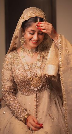 a woman in a wedding dress is smiling and holding her veil over her head while sitting on a chair