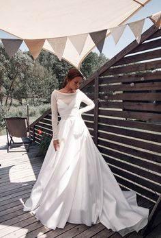 a woman in a white wedding dress standing on a wooden deck next to an awning