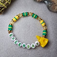 a green and yellow beaded bracelet with an animal charm on the clasp that says green bay