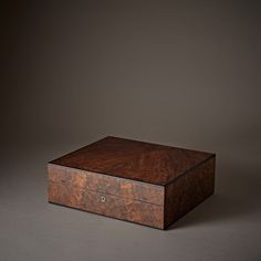 a wooden box sitting on top of a gray surface with no one around the lid