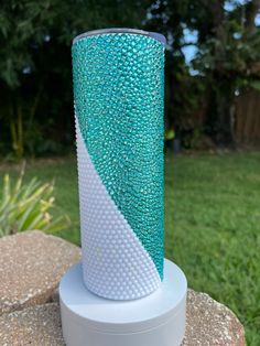 a blue and white vase sitting on top of a rock in front of some grass