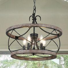 a chandelier with four lights hanging from it's center beam in front of a window