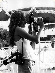 a black and white photo of a woman holding a camera