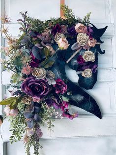 a large bouquet of flowers is hanging on the front door with an iron mask as decoration