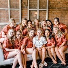 a group of women sitting next to each other in front of a brick wall and window