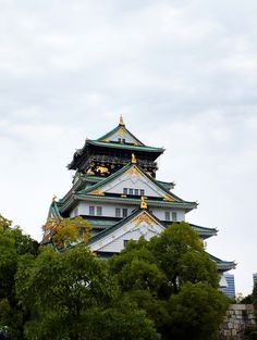 a tall white and gold building with trees in front of it on a cloudy day