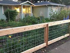 a fenced in garden with flowers and plants growing on it next to a house