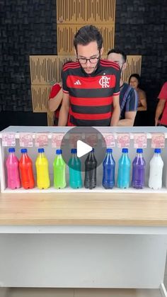 a man standing in front of a counter with lots of different colored bottles on it