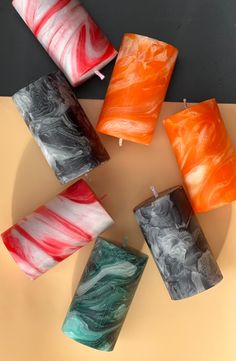 several different colored candles sitting on top of a table next to each other with wax paper wrapped around them