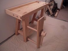 a wooden workbench sitting on top of a hard wood floor next to a wall