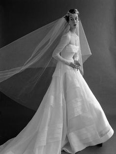 a black and white photo of a woman in a wedding dress with a veil over her head