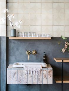 a bathroom sink sitting under a window next to a shelf filled with vases and glasses