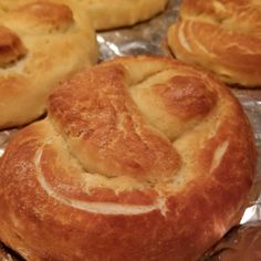 bread rolls with smiley face drawn on them sitting on tin foil covered baking pans