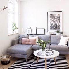 a living room with black and white striped rug, gray sectional couch, and framed pictures on the wall