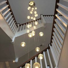 a chandelier hanging from the ceiling in a room with white walls and stairs