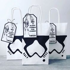 three white bags with black and white designs on them, one has a tag attached to it