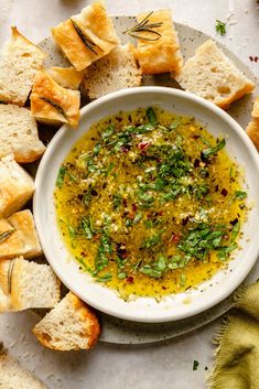 a white bowl filled with olive oil surrounded by bread slices and sprinkles