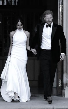 a man and woman in formal wear holding hands while walking out of a building together