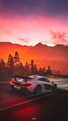 a white sports car driving down the road at sunset