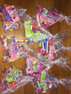 many different types of candy in plastic bags on a wooden floor with one bag full of them