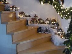 christmas decorations are on the stairs in front of a wall with lights and garlands