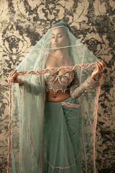 This enchanting dusty turquoise saree is crafted from delicate net fabric, radiating an ethereal charm that captivates the imagination. Paired with a matching net blouse adorned with a flair of pink, it emanates a bridal and festive aura that is simply irresistible. So mesmerizing is its allure that one might be compelled to invent an occasion just to don its elegance and grace. Perfect for weddings, celebrations, or any special event, this saree is a true embodiment of beauty and festivity, des Turquoise Saree, Placement Pattern, Cutdana Embroidery, Green Drapes, Net Blouse, Net Embroidery, Saree And Blouse, Net Blouses, Simply Irresistible