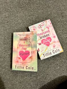 two books sitting on top of a couch next to each other, one has a pink heart in it