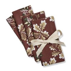 three napkins with brown and white flowers on them, tied in a bow at the end