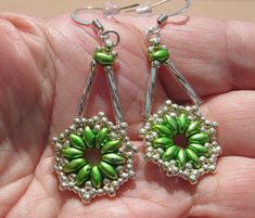 a pair of earrings with green beads and silver findings on the end of each ear